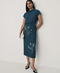A woman wearing a teal two-piece outfit with floral sequins and black heels stands against a plain white background. carousel Product Image 1