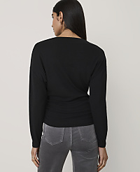 A woman wearing a black long-sleeved top and grey pants stands with her back to the camera against a plain light grey background. carousel Product Image 2
