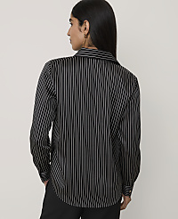 A woman wearing a black and white pinstriped shirt and black trousers stands against a plain light gray background. carousel Product Image 2