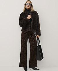 A woman wearing a brown faux-fur jacket, leopard-print trousers, and sunglasses stands against a plain white background. carousel Product Image 3