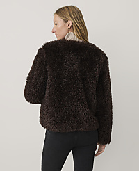 A woman wearing a dark brown faux-fur jacket and black jeans stands against a plain, light-colored background. carousel Product Image 2