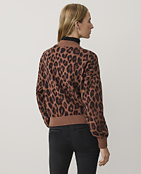 A woman wearing a leopard-print sweater and black jeans stands against a plain white background. carousel Product Image 2
