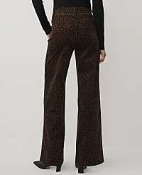 A person wearing a black top and brown leopard-print wide-leg trousers stands against a plain light gray background. carousel Product Image 3