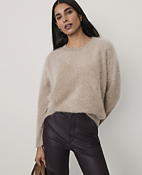 A woman wearing a fuzzy beige sweater and dark purple leather pants stands against a plain, light-colored background. carousel Product Image 1