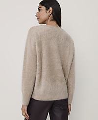 A woman wearing a fuzzy beige sweater and dark trousers stands against a plain, light-colored background. carousel Product Image 2