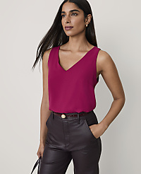 A woman wearing a magenta V-neck top and dark leather trousers stands against a plain, light-colored background. carousel Product Image 1