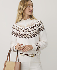 A blonde woman wearing a patterned white sweater and white pants stands against a plain light gray background. carousel Product Image 1