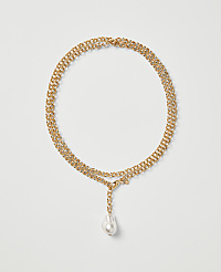 A gold chain necklace with a single white pearl drop pendant rests on a plain light gray background. carousel Product Image 1