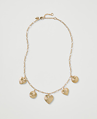 A gold chain necklace with heart and circular ribbed charms rests on a plain light gray background. carousel Product Image 1