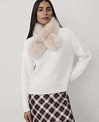 A woman wearing a white sweater with a faux-fur collar and a plaid skirt stands against a plain, light-colored background. carousel Product Image 1