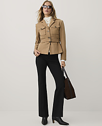 A woman wearing a belted tan jacket, black trousers, and sunglasses stands against a plain white background. carousel Product Image 2