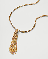 A gold chain necklace with a tassel pendant rests on a plain white background. carousel Product Image 2