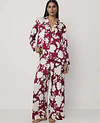 A woman wearing red and white floral pajamas stands against a plain, light-colored background. carousel Product Image 1