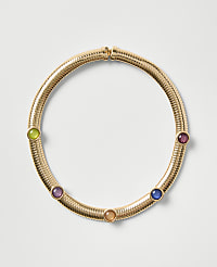 A gold ribbed necklace featuring five colorful gemstones is centered against a plain light gray background. carousel Product Image 1