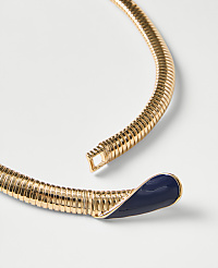 A gold-toned ribbed collar necklace with a navy blue enamel tip rests on a plain white background. carousel Product Image 2