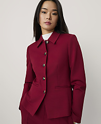 A woman wearing a red blazer and white turtleneck stands against a plain, light-colored background. carousel Product Image 1