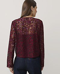 A woman wearing a burgundy lace top and dark blue jeans stands against a plain white background. carousel Product Image 2