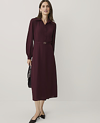 A woman wearing a long-sleeved burgundy dress and black heels stands against a plain white background. carousel Product Image 1
