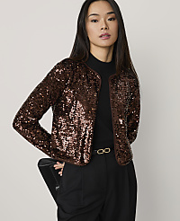 A woman wearing a shimmering brown sequined jacket and black trousers stands against a plain light gray background. carousel Product Image 1