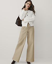 A woman wearing a white cable-knit cardigan and wide-leg khaki trousers stands against a plain white background. carousel Product Image 1