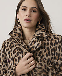 A woman wearing a leopard-print coat and gold jewelry poses against a plain, light-colored background. carousel Product Image 3