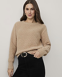 A woman wearing a tan textured sweater and black corduroy pants stands against a plain light gray background. carousel Product Image 1