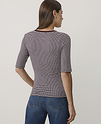 A woman wearing a maroon and white checkered top and blue jeans stands against a plain light gray background. carousel Product Image 2