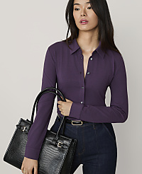 A woman wearing a purple button-down shirt and dark blue jeans holds a black crocodile-embossed handbag against a plain light gray background. carousel Product Image 1