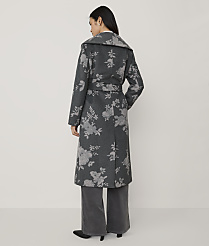A woman stands with her back to the camera wearing a long, grey floral-patterned coat and wide-leg trousers against a plain, light-colored background. carousel Product Image 2