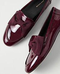 A pair of glossy burgundy patent leather loafers with bow accents are set against a plain white background. carousel Product Image 2