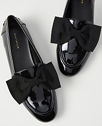 A pair of black patent leather loafers with large black bows are set against a plain white background. carousel Product Image 2