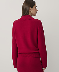 A woman wearing a red knit sweater and matching skirt stands against a plain, light-colored background. carousel Product Image 2