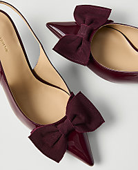 Two burgundy patent leather pointed-toe heels with large bows are positioned against a plain white background. carousel Product Image 2