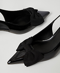 Two black patent leather pointed-toe heels with decorative bows sit against a plain white background. carousel Product Image 2