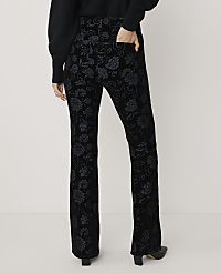 A person wears black floral patterned trousers and a dark sweater against a plain white background. carousel Product Image 3