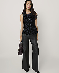 A woman wearing a black patterned vest and black leather flared trousers stands against a plain, light-colored background. carousel Product Image 3
