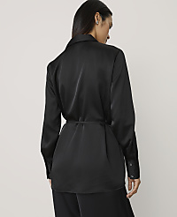 A woman wearing a black satin belted blazer and matching trousers stands against a plain, light-colored background. carousel Product Image 2