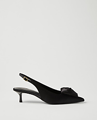 A black satin slingback heel with a decorative bow sits in the foreground against a plain, light gray background. carousel Product Image 1