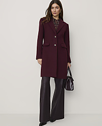A woman wearing a long burgundy coat and wide-leg dark purple trousers stands against a plain, light-colored background. carousel Product Image 1