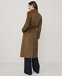 A woman wearing a long brown belted coat and wide-leg dark denim jeans stands against a plain, light-colored background. carousel Product Image 2