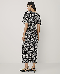 A woman wearing a black and white floral midi dress and black heels stands against a plain white background. carousel Product Image 2
