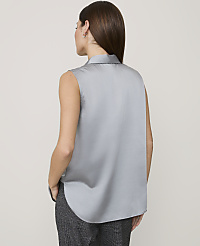 A woman wearing a sleeveless grey satin blouse and dark patterned trousers stands against a plain light grey background. carousel Product Image 2