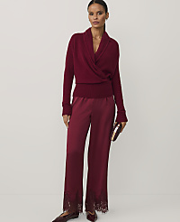 A woman wearing a burgundy wrap sweater and matching satin trousers with lace hems stands against a plain white background. carousel Product Image 1