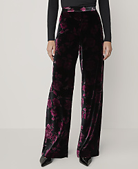 A person wears wide-leg black and purple floral velvet trousers and a black top against a plain light grey background. carousel Product Image 2