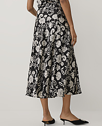 A person wears a black and white floral midi dress and black pointed-toe mules against a plain white background. carousel Product Image 3