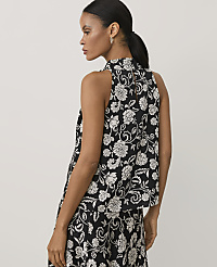 A woman wearing a black and white floral print sleeveless top and matching skirt stands against a plain light grey background. carousel Product Image 2