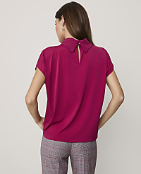 A woman stands with her back to the camera wearing a magenta short-sleeved blouse and plaid trousers against a plain light gray background. carousel Product Image 2