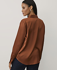 A woman wearing a copper-colored satin shirt and dark blue jeans stands against a plain, light gray background. carousel Product Image 2