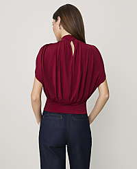 A woman wearing a maroon blouse and dark blue jeans stands with her back to the camera against a plain light gray background. carousel Product Image 2