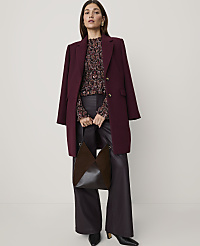 A woman wearing a burgundy coat, patterned blouse, and dark leather trousers stands against a plain white background. carousel Product Image 3